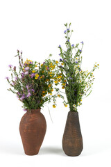 Two handmade ceramic vase with a bouquet of flowers isolated on white background.