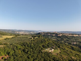 Obraz premium Aerial drone photo of Orvieto, a historic town in Umbria, central Italy, dramatically perched on a volcanic plateau. The view captures the hilltop town surrounded by olive groves, lush countryside.