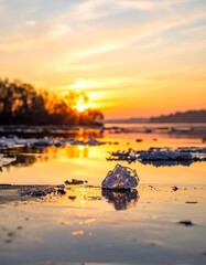 A captivating ice shard rests on the frozen water's surface, reflecting the warm hues of a breathtaking sunset.