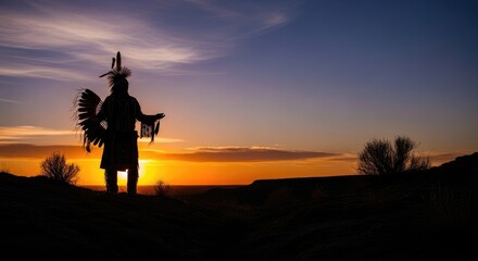 Vivid sunset illuminates indigenous person silhouette standing on hill, adorned with traditional headdress, embracing tribal heritage and ancient wisdom.