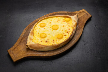Traditional Georgian Adjarian khachapuri with eggs and cheese on a wooden board