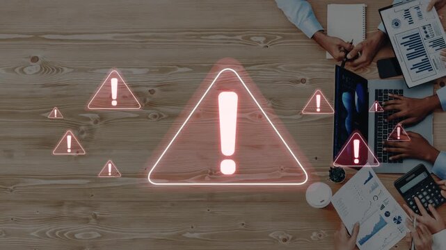 A modern office scene with diverse hands around a wooden table, featuring digital alert symbols to signify caution and urgency in a collaborative work environment. Raster