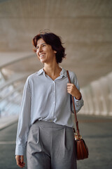 Happy businesswoman walking confidently through the city streets, smiling brightly as she embraces...