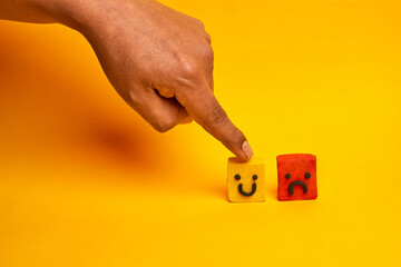 A finger choosing a happy face over a sad face illustrates customer satisfaction decision making, representing feedback evaluation and service improvement.
