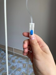 Hand holding an IV line clamp in a medical environment with a soft background