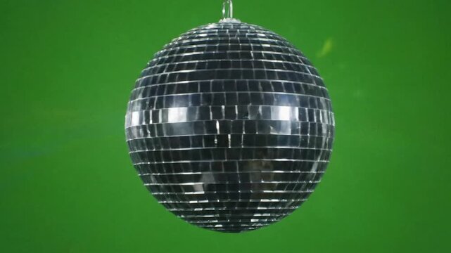 This classic glittering mirror ball decoration hangs and spins reflecting bright beams of light on the dancefloor for a vibrant nightclub celebration or a vintage themed disco party