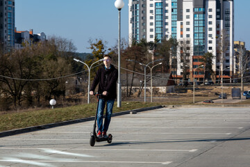 Young man riding electric scooter in city park