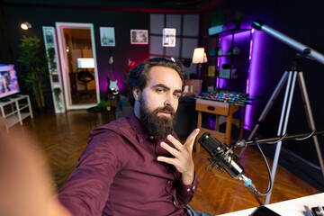 ASMR artist using quality mic and selfie camera in studio to do anti stress video, doing relaxing tingling sounds. POV of man using professional microphone to get sleep inducing audiohealing content