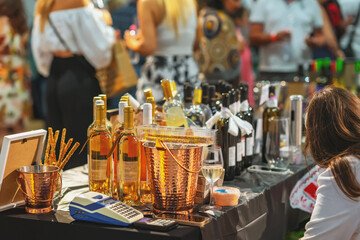 Table is filled with bottles of white and red wine, copper buckets, and glasses at a busy wine event. Concept of wine, tasting, and celebration highlighting lifestyle, elegance, social gathering.