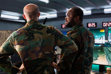 Fototapeta premium Military officer and colleague operating high tech aerial systems to support reconnaissance and target identification. Team of army specialists monitoring counterinsurgency attacks
