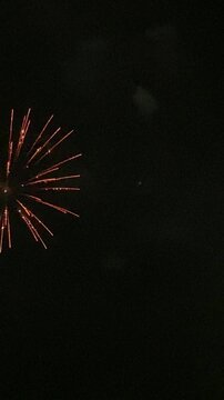 Vertical video. Fireworks on the beach celebrating the end of the fiesta. Powerful, single charges explode high in the sky. Mallorca, Spain.