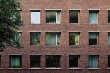 Obraz premium Urban apartment building with rectangular windows showcasing greenery and soft curtains in a modern architectural design