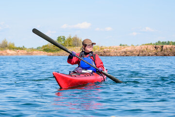 young woman kayaking on Georgian Bay, Ontario, in a red sea kayak with a black greenland style paddle, room for text © Michael Connor Photo