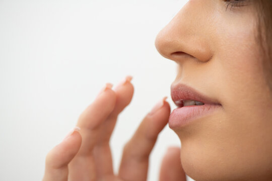 Young woman touching her dry lips, close up. Skin care and lip care concept. Selective focus.
