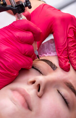Permanent tattoo makeup procedure. Eyebrow tattoo make-up. Brow tattoo. Close up, selective focus