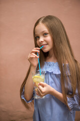Cute little girl drinks lemonade.