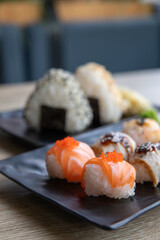 Temarizushi or Japanese rice balls with Onigiri or Japanese rice triangle served on on the black plate in the restaurant Temari zushi with seafood. Kimbab or gimbap - rice triangle. Selective focus.