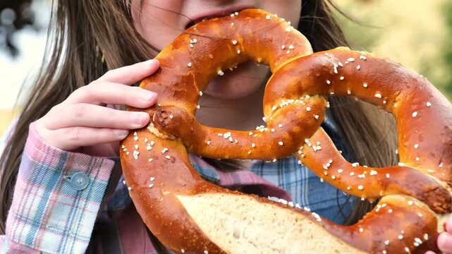 Child eating pretzel and smiling. Oktoberfest food traditional. Bretzel in the hands of a child. Bavarian traditional pastry. 
