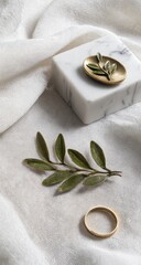 Elegant gold ring and olive branch on white textured background.
