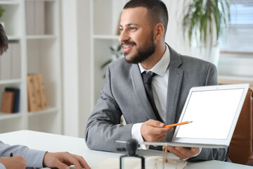 Naklejka premium Male lawyer showing laptop to client at office