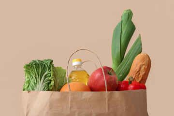 Naklejka na ściany i meble Paper bag with different groceries on beige background, closeup