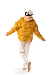 Young woman in stylish puffer jacket listening to music on white background, back view