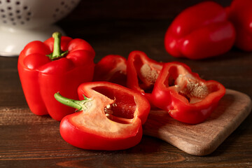Cutting board with cut red bell pepper on wooden background