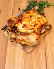 Whole Roasted Chicken with Golden Skin and Herbs on Wooden Table for Premium Meat Object and Dinner Concept
