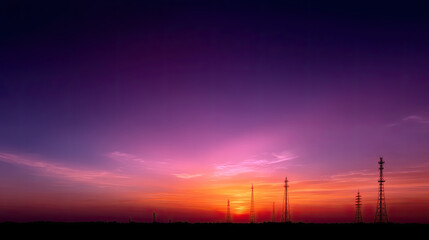 Fototapeta premium Stunning sunset casts vibrant hues across sky, with silhouettes of communication towers standing tall against colorful backdrop. scene evokes sense of tranquility and beauty