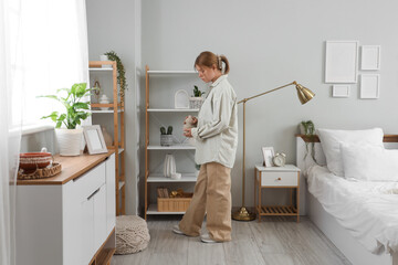 Fototapeta premium Female interior designer with stylish vase in bedroom