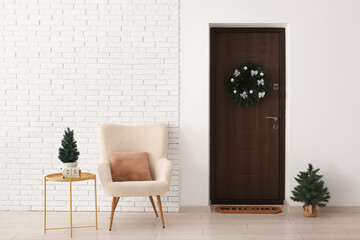 Interior of hallway decorated for Christmas with door, fir trees and armchair