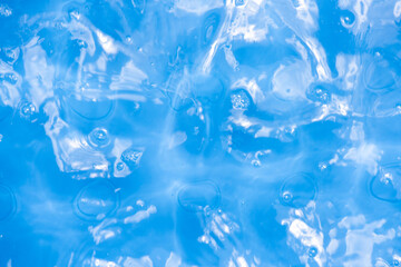 Blue water with ripples on the surface. Defocus blurred transparent blue colored clear calm water surface texture with splashes and bubbles. Water waves with shining pattern texture background.