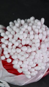 Vertical video cotton swabs rotating, cotton buds on black background top view. Personal hygiene and cosmetic items. Ear cleaning q-tips