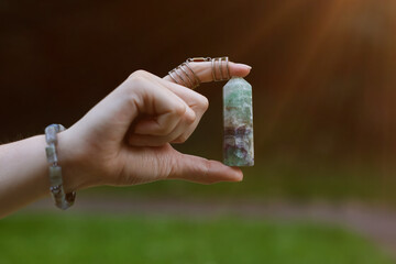Woman meditating with crystal to heal or restore her aura outdoors, closeup