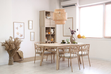 Interior of light dining room with table, shelf unit and pumpkins