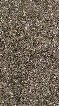 Vertical video chia seeds rotating background close up top view. Seed of chia or Salvia hispanica, mint family, hygroscopic. Healthy nutrition, dieting concepts, tasty and healthy food.