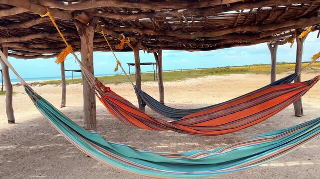 Colorful hammocks under wooden tent on sandy beach in La Guajira Colombia