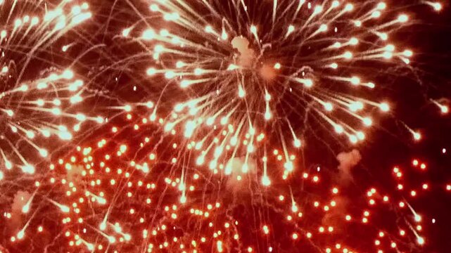 A grand display over the city, featuring brilliant trails of light exploding outward. Sparkling embers linger momentarily before fading into the darkness of the New Year's Eve sky.