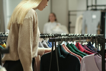A girl tries on a striped sweater in a store. A young woman chooses clothes in a store while shopping. Seasonal holiday discounts on purchases. Black Friday