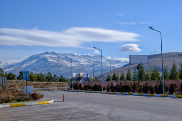 Rural landscape in Turkey with snow-covered hills, fir trees, blue sky 