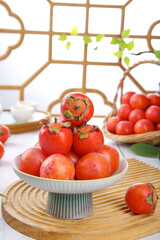 Fresh Shanxi Persimmons on Ceramic Stand with Traditional Chinese Lattice Window Background