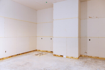 Room bare walls covered with drywall panels, indicating ongoing renovation work.