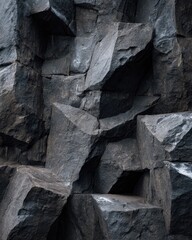 Detailed close up of dark rough stone texture with sharp geometric facets and dramatic shadows.
