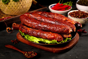 Homemade Smoked Sichuan Pork Sausages with Spicy Red Peppers and Traditional Chinese Seasonings on Wooden Board