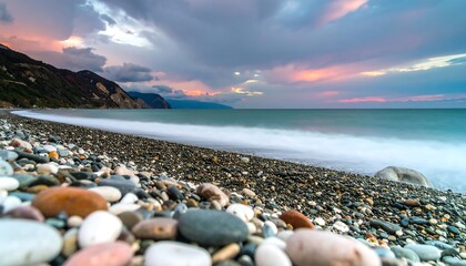 Colorful pebble beach meets a tranquil ocean at sunset
