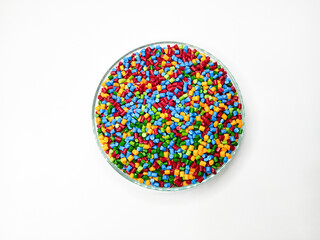 Top view, masterbatch granules, polymer carrying pigment poured into a glass cup forming a circle with a white background, as a product catalog design for a plastic industry company profile