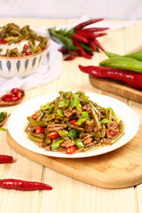 Stir-fried pickled green beans with minced pork and chilies on wooden cutting board