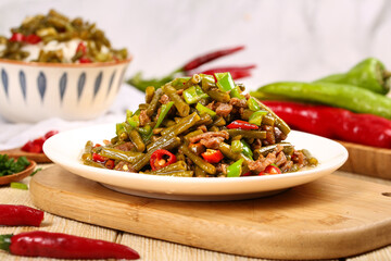 Stir-fried pickled green beans with minced pork and chilies on wooden board - Asian cuisine