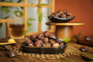 Obraz premium Roasted Alpine Chestnuts in Traditional Kitchen Setting with Tea Service and Bamboo Accessories