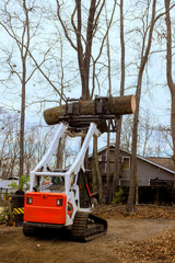 Equipment is used to lift transport large tree logs in wooded residential neighborhood